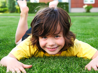 Happy girl lies on the lawn. Joyful emotions. Cut grass. Summer.