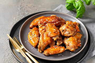 Homemade baked or fried chicken wings in barbecue sauce in a plate on the cooking table