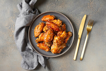 Homemade baked or fried chicken wings in barbecue sauce in a plate on the cooking table top view with copyspace	
