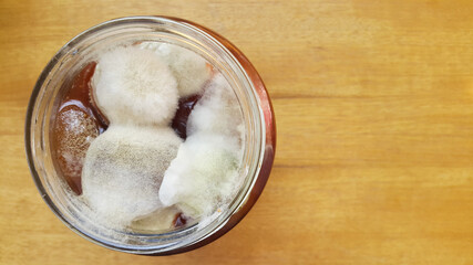 Mold on fig jam in a jar top view. Mold spores on preservation. Spoiled jam in a glass jar. A poisonous mushroom.