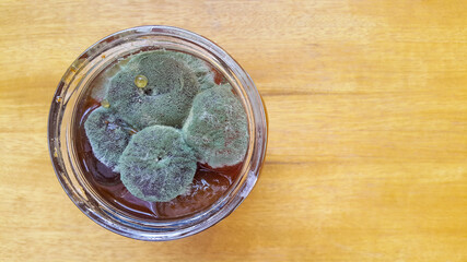Mold on fig jam in a jar top view. Mold spores on preservation. Spoiled jam in a glass jar. A poisonous mushroom.
