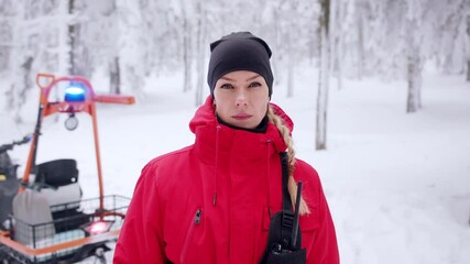 Paramedic woman from mountain rescue service with walkie talkie outdoors in winter in forest.