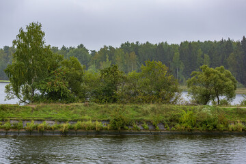 Scenic river landscape with green trees in early autumn