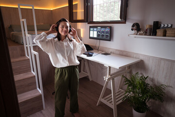 Asian broker putting on headset against monitor with graphs