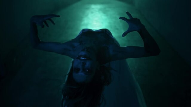 Dead walking zombie woman in dark corridor and mist close-up. Creepy bride wearing wedding dress with veil. Deceased fiancee returned to life. Horrible klip on halloween. Haunted house. 