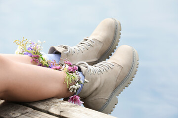 Naklejka premium Woman sitting on wooden pier with flowers in socks outdoors, closeup