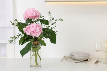 Beautiful pink hortensia flowers in vase on kitchen counter. Space for text