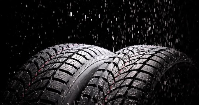 Winter Car tire with snow flakes on black background. Winter season.
