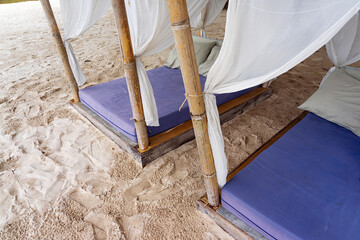 Empty violet beach beds with white curtains on sand beach