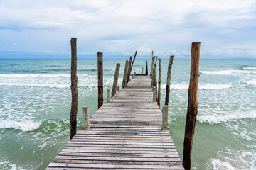 Wooden pier with sea waves and blue sky background