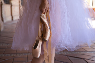 detail of ballet dancer's hands holding shoes with her hands. Classical ballet