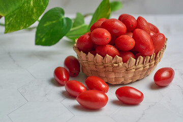 Stack of wet cherry tomatoes in a wooden basket, freshly harvested.