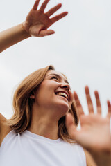 Young caucasian woman dancing outdoor gesturing with hands feeling free smiling having fun