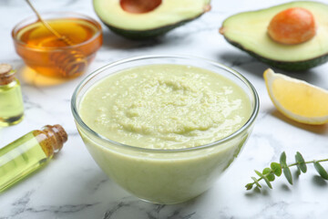 Homemade hair mask in bowl and ingredients on white marble table, closeup