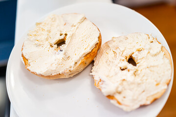 Bagel bread toasted slices closeup on white plate topped with cream cheese plain as breakfast...