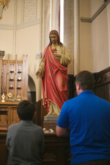 Fototapeta premium Father and son in front of Sacred Heart of Jesus Statue in a Catholic Church