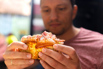 Young man holding in hands classic Maine lobster roll sandwich in brioche bun bread in seafood...