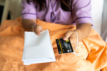 Asian fat woman patients lying in hospital patient bed and show creditcard mock up in hand.