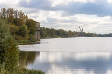Fototapeta na wymiar River backwater with port cranes and a water intake building