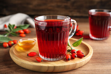 Fresh rose hip tea, honey and berries on wooden table