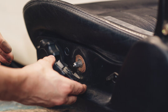 Repair Of The Old Car Seat. Car Mechanic's Hands Is Using Tools.