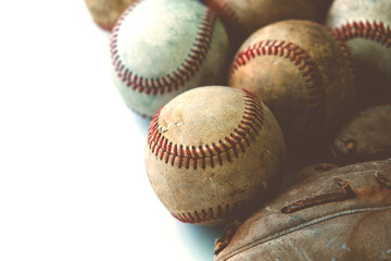 Old leather baseball glove with used balls from game with copy space on white background.