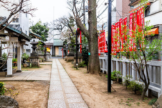 Tokyo, Japan - March 28, 2019: Kaichu inari Shinto shrine in Shinjuku with red banners and path in garden and purification fountain with nobody