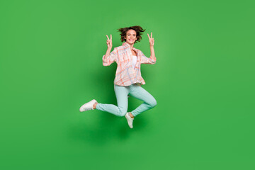 Fototapeta na wymiar Full size photo of cheerful happy young woman jump up make fingers v-signs cool isolated on green color background
