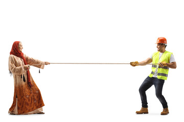 Full length profile shot of a woman with a hijab pulling a rope against a construction worker