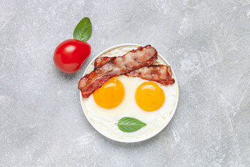 English breakfast - eggs, bacon and basil leaves in a plate. Top view