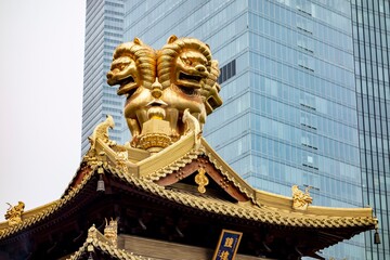 Fototapeta na wymiar Golden lion statues on a roof of Jingan Temple in the centre of Shanghai, China