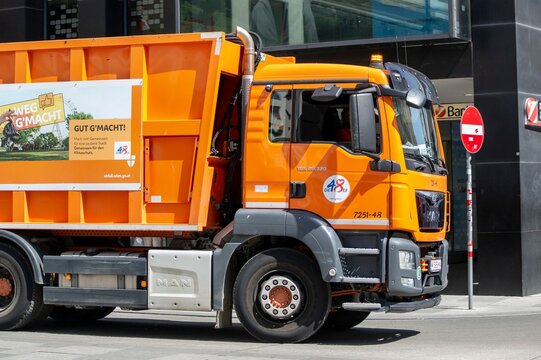 Orange dumpster truck MAN TGS 26.320 in the centre of Vienna removing the garbage