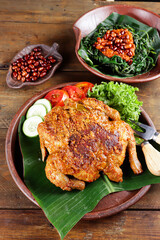 Ayam bakar Taliwang  is a traditional roast chicken from Lombok Indonesia on a wooden background, served with plecing.