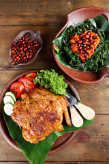 Ayam bakar Taliwang  is a traditional roast chicken from Lombok Indonesia on a wooden background, served with plecing.