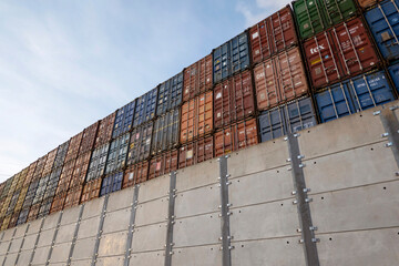 Southampton, England, UK. 2021.  Metal containers in a high stack appear over a high security  concrete wall,