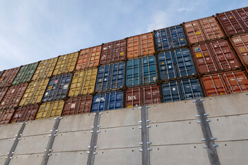 Southampton, England, UK. 2021.  Metal containers in a high stack appear over a high security  concrete wall,