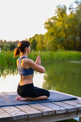 Fototapeta premium A woman is doing exercises on the lake. The concept of keeping fit.