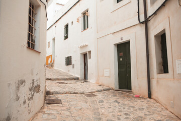Fototapeta na wymiar The architecture of the island of Ibiza. A charming empty white street in the old town of Eivissa
