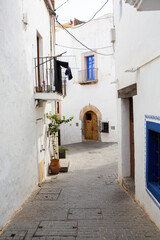 Fototapeta na wymiar The architecture of the island of Ibiza. A charming empty white street in the old town of Eivissa