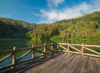 Wooden pier on the lake in the morning sun. Beautiful nature and lake view
