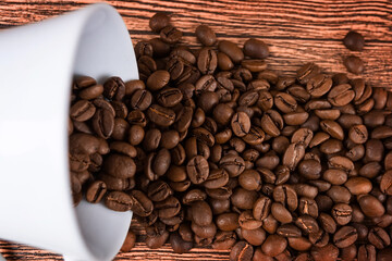 Black coffee foil packaging bag on wooden table top view. Spilled beans flat lay concept. Room for text.