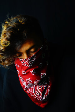 Closeup Of A Stylish Indian Male Wearing A Red Bandana Over His Face Posing On The Dark Background