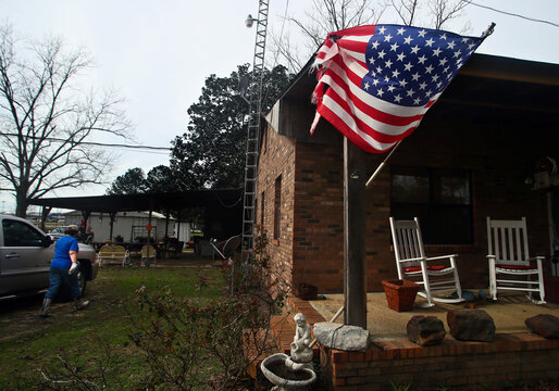 Margie Peters heads to check on her baby goats as a tattered flag stands on her porch after a deadly storm hit Rehobeth