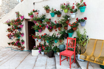 Fototapeta na wymiar Red wooden chair in front of a facade full of flower pots