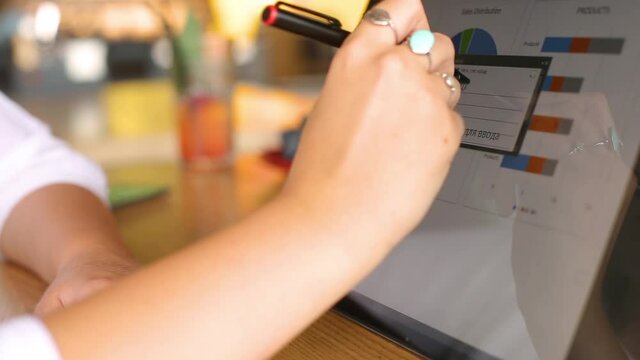 Businesswoman hand pointing with stylus on the chart over convertible laptop screen in tent mode. Woman using 2 in 1 notebook with touchscreen for work on business presentation. Isolated close view.