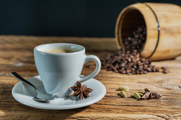 espresso cup with black roasted coffee beans in the background on an old wooden table top.