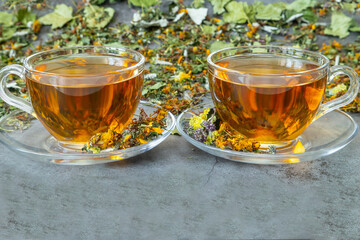 Two glass cups of herbal tea on gray background.