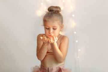 Sincere happiness. Happy joyful girl holding her hands and blowing gold glitter. 