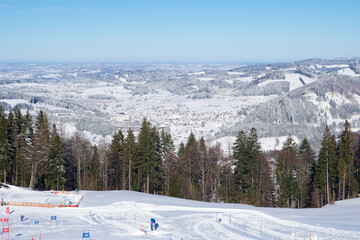 Fototapeta na wymiar OBERSTAUFEN, GERMANY - 29 DEC, 2017: Beautiful view of the snowy winter resort Oberstaufen with a ski slope in the foreground in the Bavarian Alps