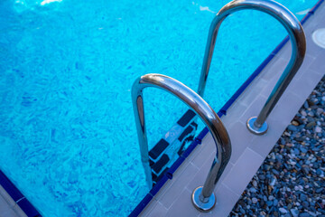 Background of blue transparent water in the swimming pool on the territory of the hotel. Descent to...